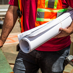 man-wearing-safety-vest-holding-drafting-papers-close-up
